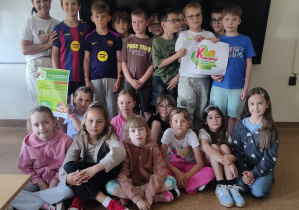 nauczyciel z uczniami klasy 2a, którzy pozują z plakatami programu „Kubusiowi Przujaciele Natury”