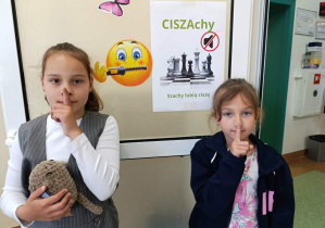 Dziewczynki na tle plakatu „Szachy lubią ciszę”
