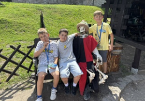 Chłopcy pozują obok szkieletu ubranego w historyczny strój.