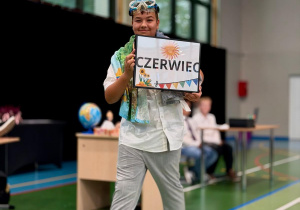 Uczeń prezentujący tabliczkę z nazwą miesiąca