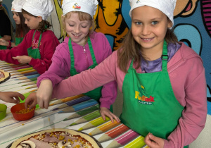 dziewczynki układają dodatki na pizzy
