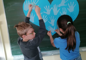 Dzieci przyklejają dłonie na sercu.