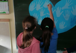 Dziewczynki przyklejają dłonie na sercu.