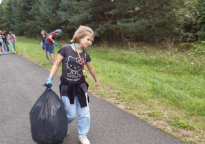 uczennica klasy 7 niesie ciężki worek śmieci