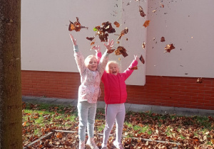 Dziewczynki sypią liście do góry.