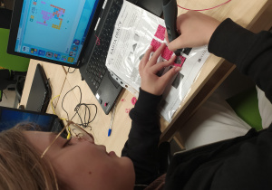 uczennica projektuje kostkę za pomocą długopisów 3D