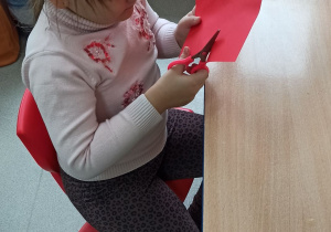 Dziewczynka wycina serduszko z papieru.