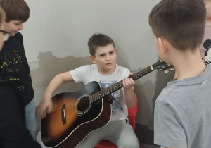 Uczeń próbuje grać na gitarze.