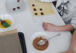 uczennica układa kostki czekolady na cieście