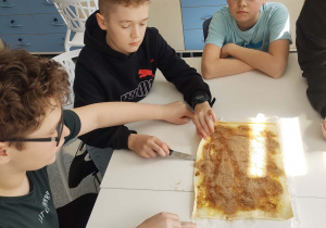 uczniowie patrzą na obsypany cynamonem arkusz ciasta