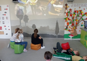 Uczniowie siedzą i oglądają film.