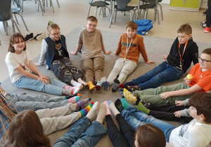 uczniowie siedząc w kole prezentują kolorowe skarpety