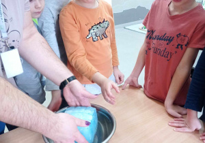 Nauczyciel wkłada kawałek lodu do miski