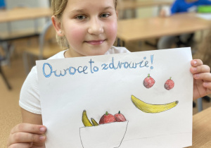 Dziewczynka z plakatem zachęca do jedzenia owoców i warzyw.