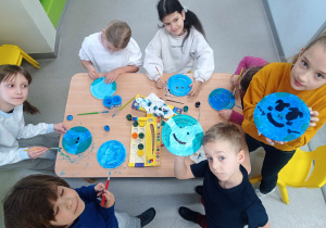 Uczniowie wykonują farbami prace plastyczne.